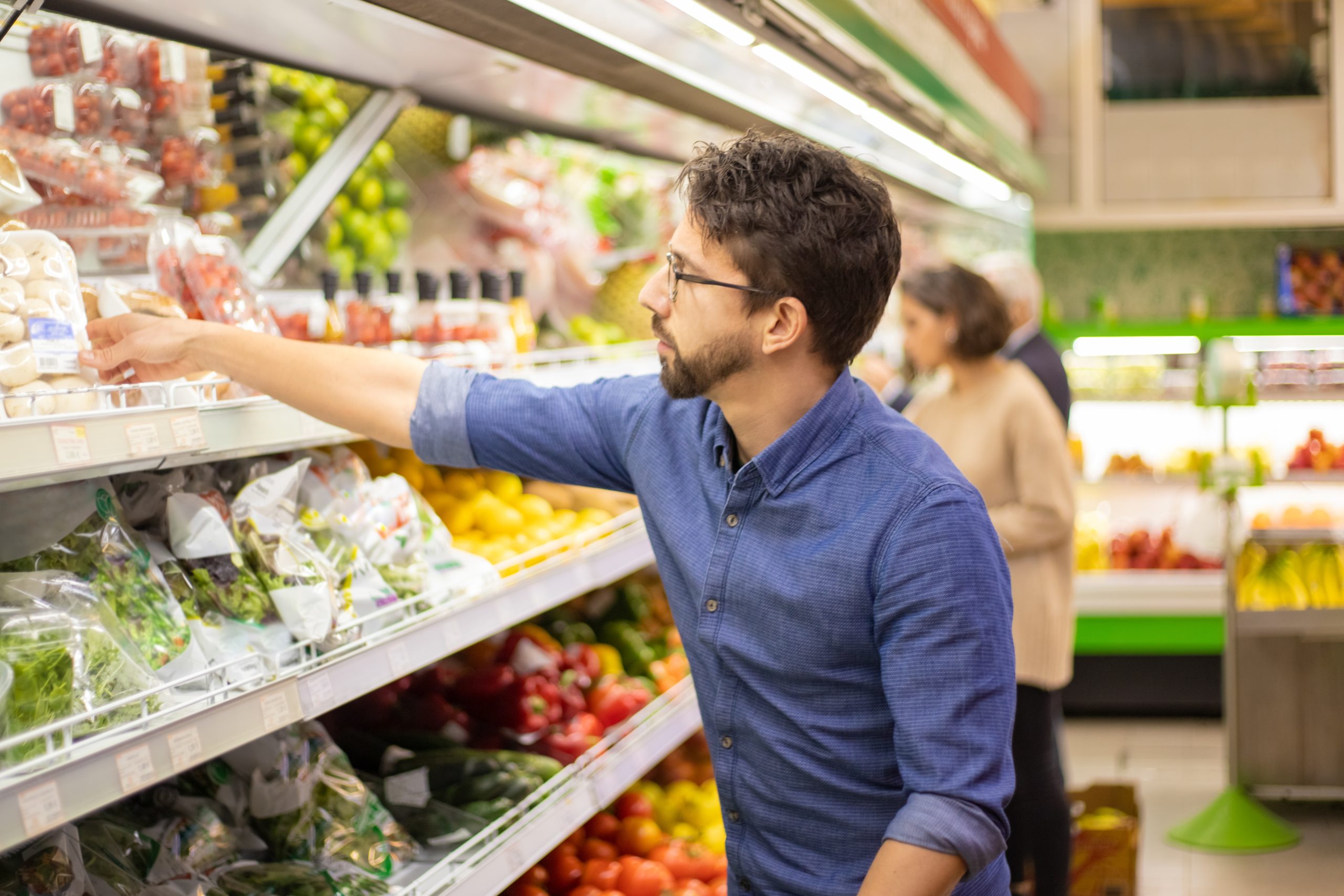 Man reaching for produce in grocery store