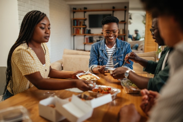 Group of friends eating takeout at a table.