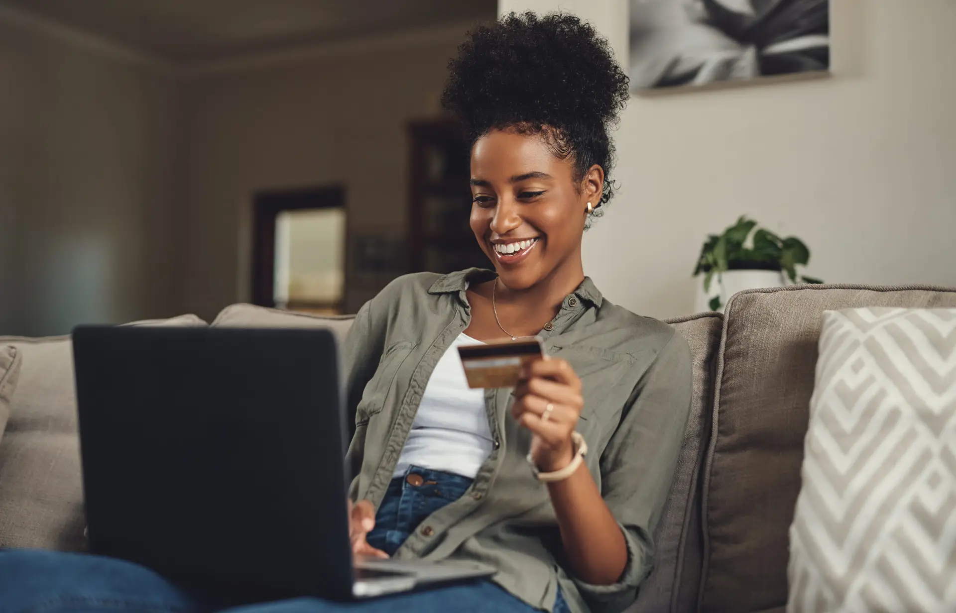 Woman, laptop and relax with credit card on sofa for online shopping for home decor, browsing and digital marketplace. Girl, technology and internet banking in house for virtual retail and buying