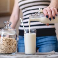 woman pours oat milk Woman pouring oat milk
